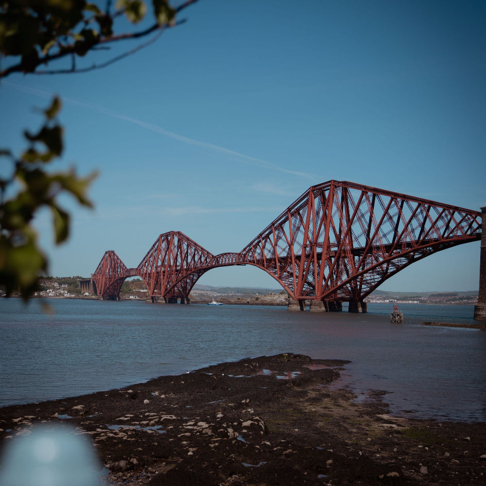 Red steel bridge over water with clear blue sky