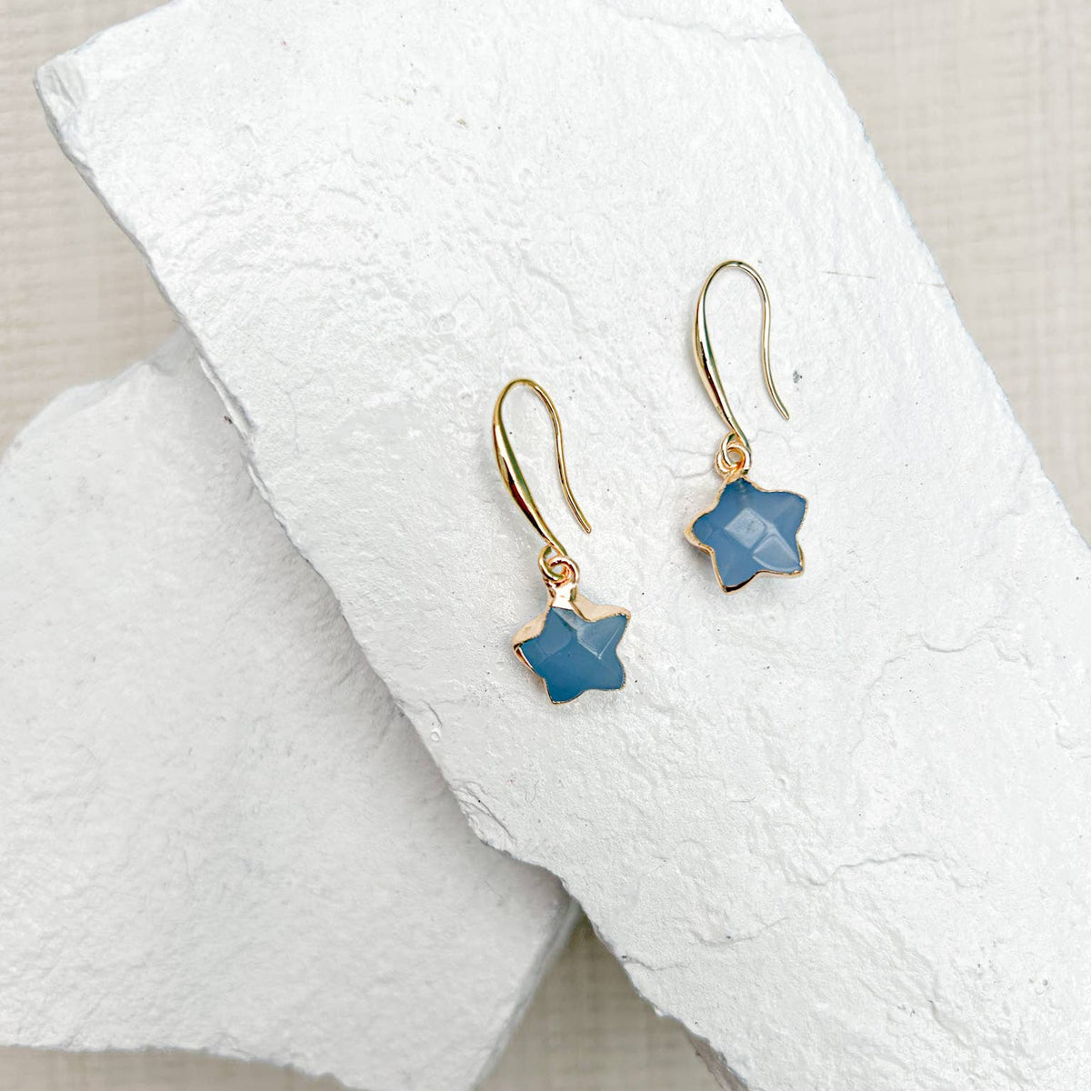 Pair of star-shaped earrings on a white towel