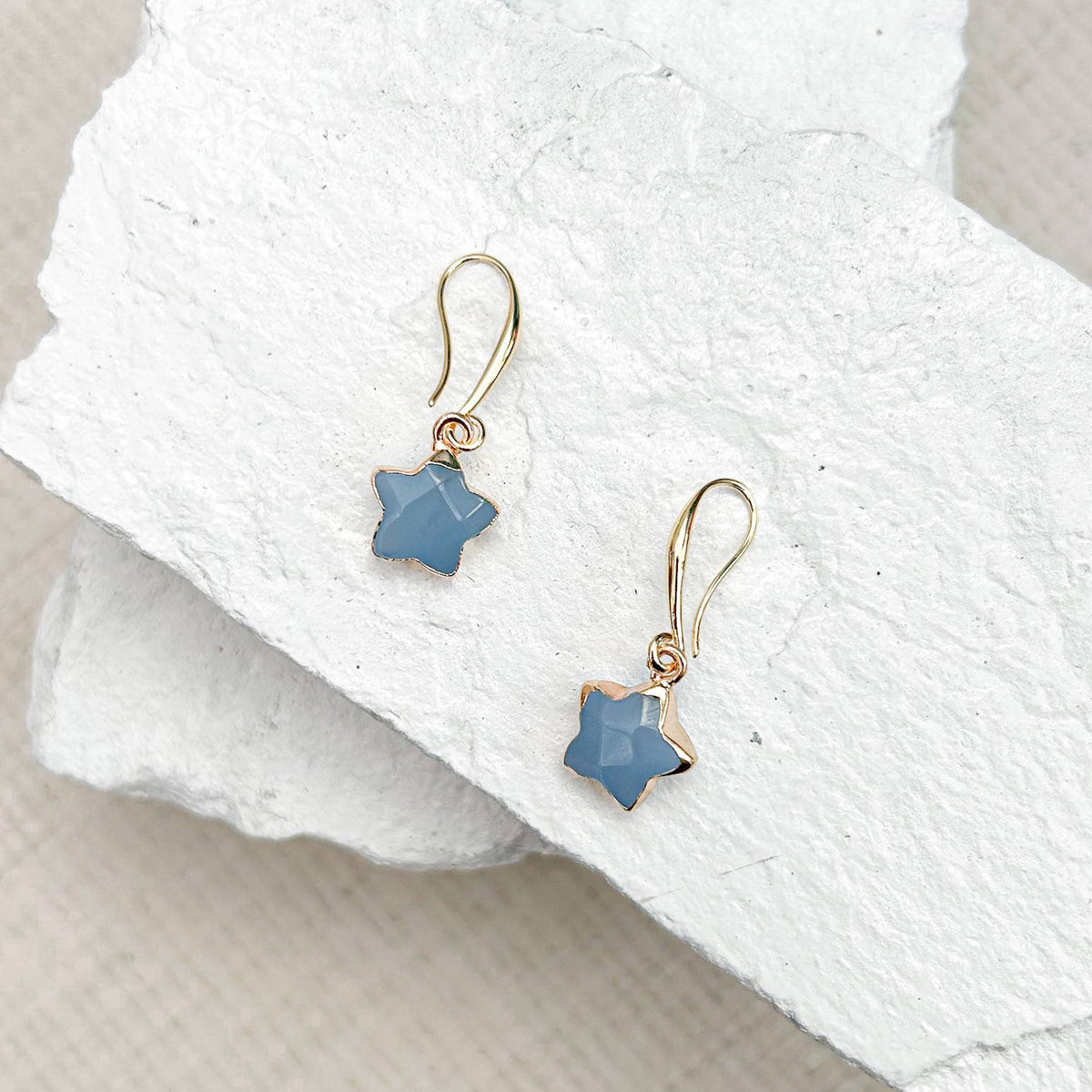 Blue star-shaped earrings on a white towel
