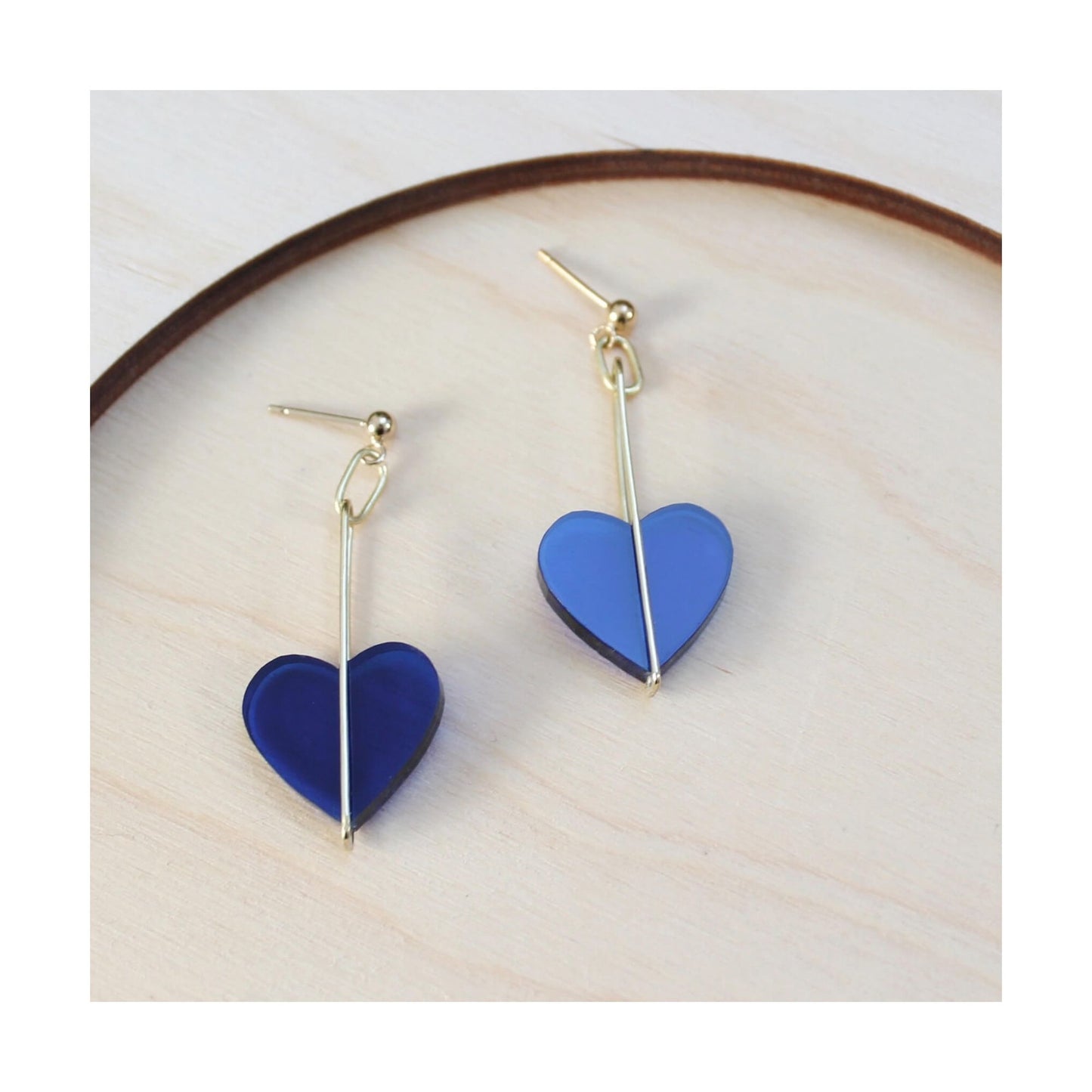 A pair of earrings featuring blue perspex hearts dropped from a sterling silver post and wire fitting.