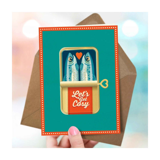 A bold, delightfully illustrated love or friendship card by The Typecast Gallery. It features a pair of sardines in a cute tin with the words "Let's Get Cosy" on the label. 