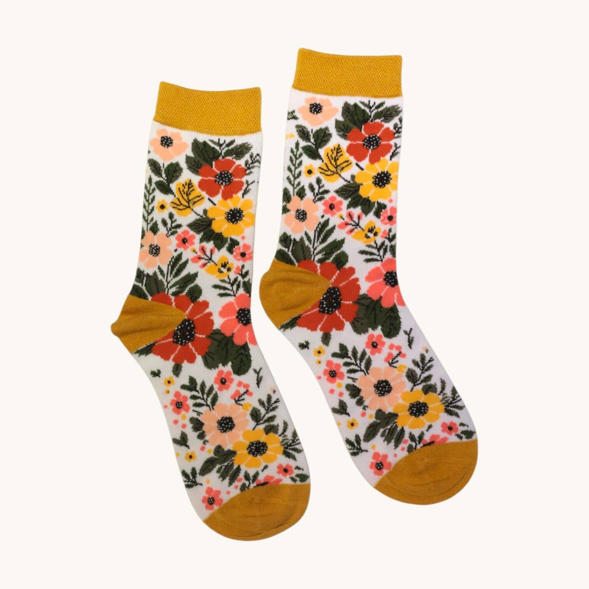 A pair of crew socks with a vibrant floral pattern on a white background, featuring mustard yellow cuffs, heels, and toes. The floral print includes red, orange, yellow, and pink flowers with green leaves.