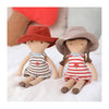 Lydie and Hugo, super soft jersey dolls wearing striped rompers and linen hats. Hugo has curly brown short hair and Lydie has long brown hair in plaits.