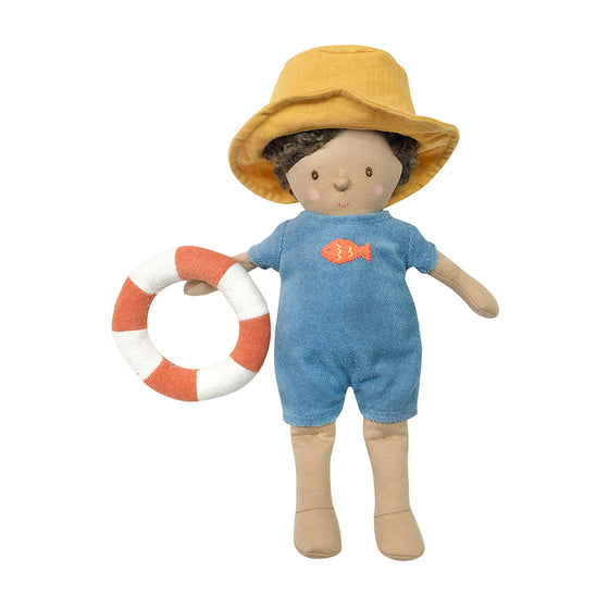 A little baby boy cotton doll set. This doll wears a blue romper with an embroidered fish on his chest. He also wears a yellow sunhat and is holding a rubber ring. Ready for swimming!